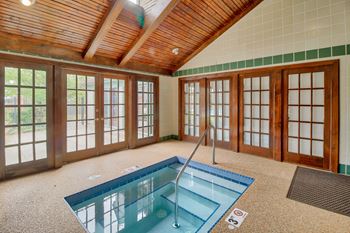 Indoor swimming pool in a room with windows and a wooden ceiling